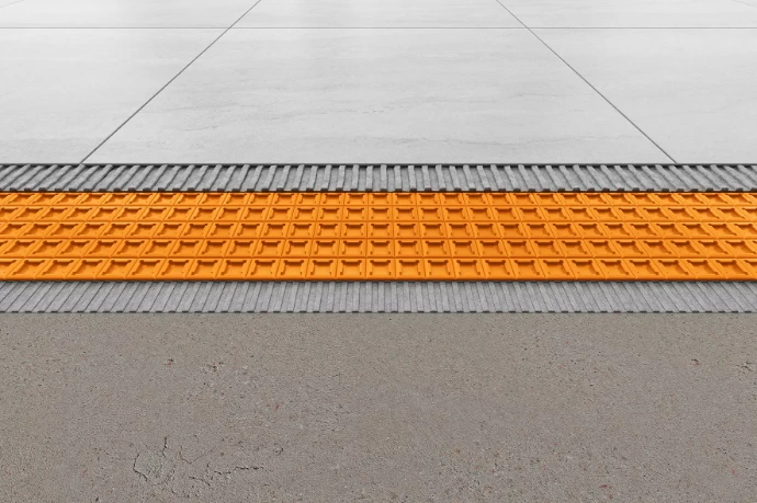 Detail van oranje ontkoppelingsmat geplaatst tussen chape en tegelvloer voor vloerverwarming